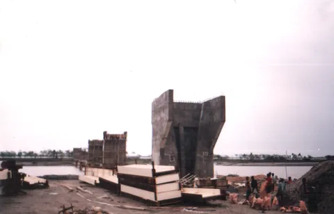 Large concrete bridge abutment under construction on a riverbank