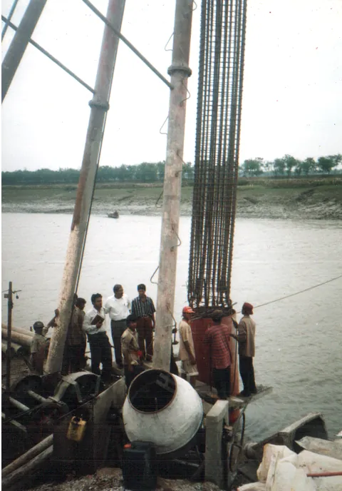Crew driving piles into a riverbed
